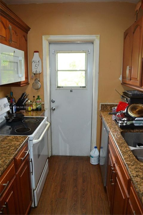 Kitchen featuring wood cabinetry, stone-finish countertops, wood-finish flooring, an over-the-range microwave, and a glass-inset door