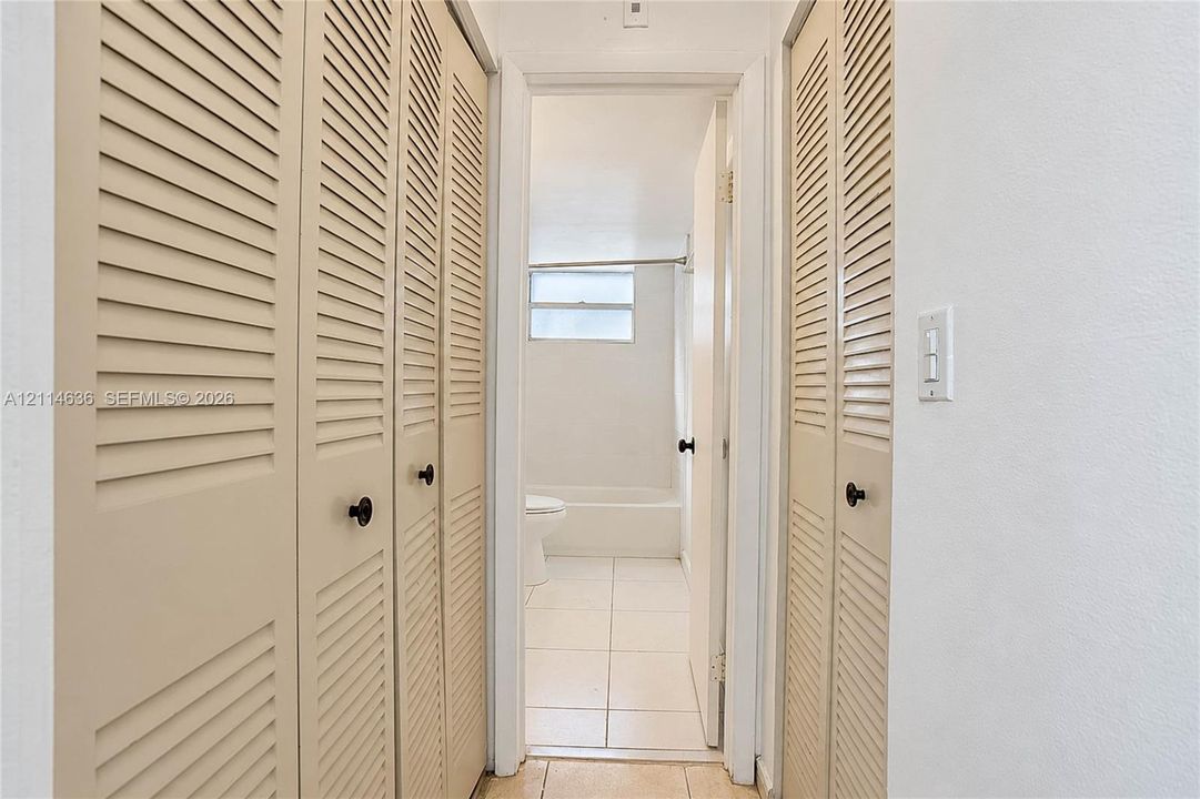 Floor-to-ceiling bi-fold louvered closet doors and tile flooring