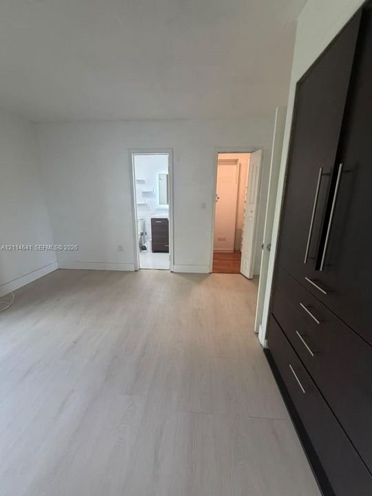 Wood-finish flooring, integrated dark-toned cabinetry with metal hardware, and interior doorways
