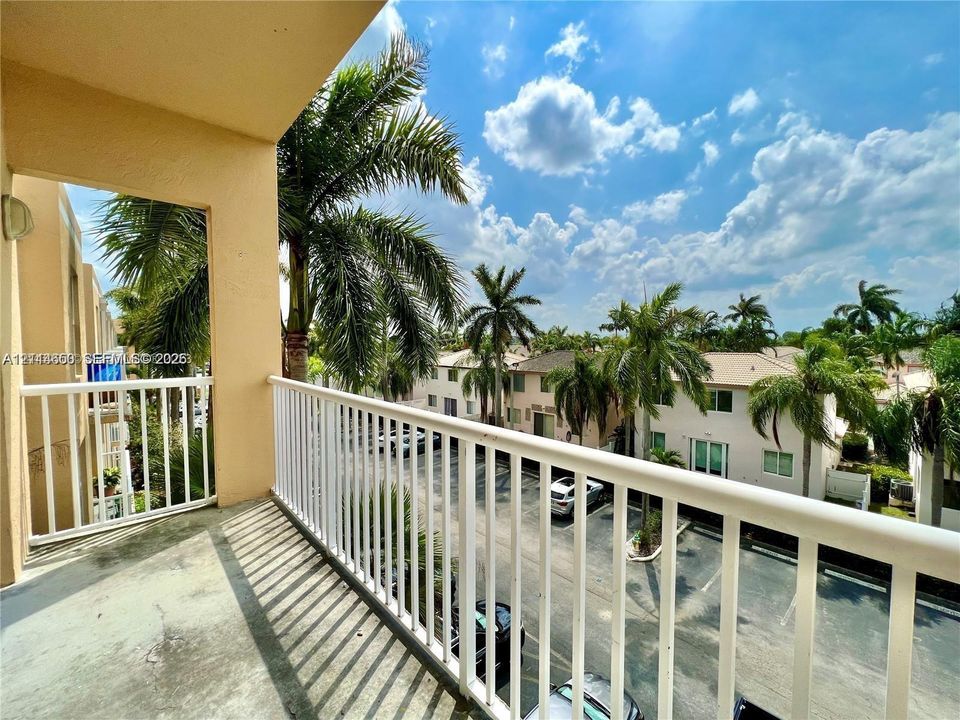 Covered balcony featuring concrete flooring and a white metal railing