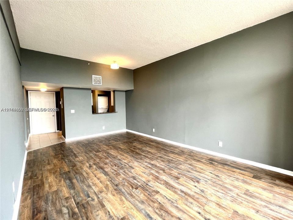 Interior space featuring wood-finish flooring, vaulted ceilings, and a pass-through opening to the kitchen