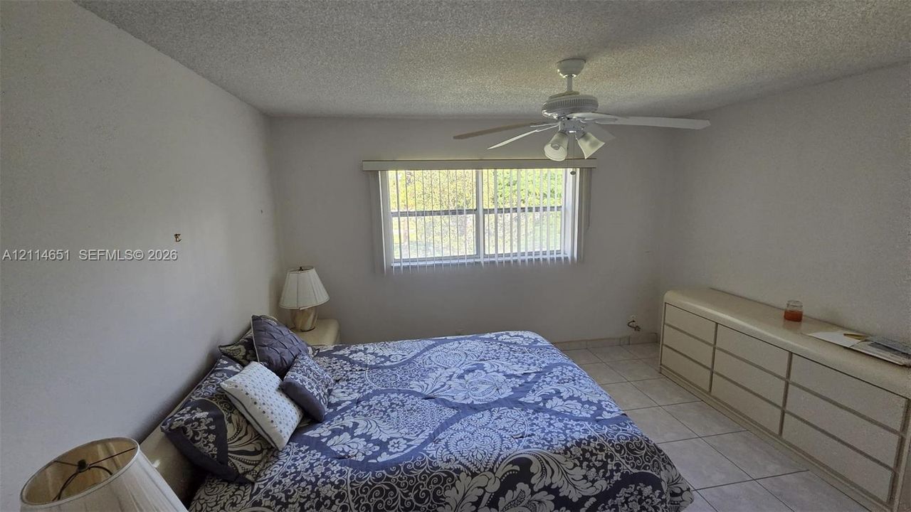 Interior room featuring tile flooring, a central ceiling fan with integrated lighting, and a window with vertical blinds