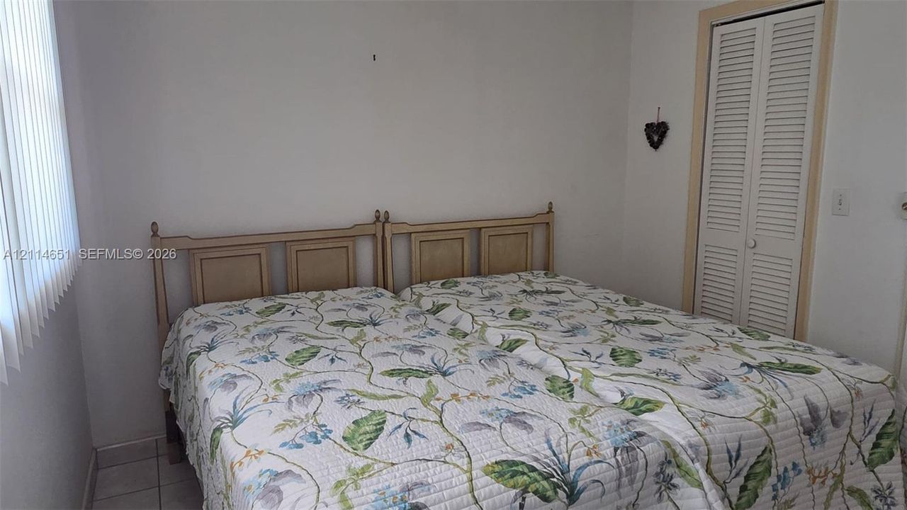 Room featuring white walls, tile flooring, and a closet with white louvered doors