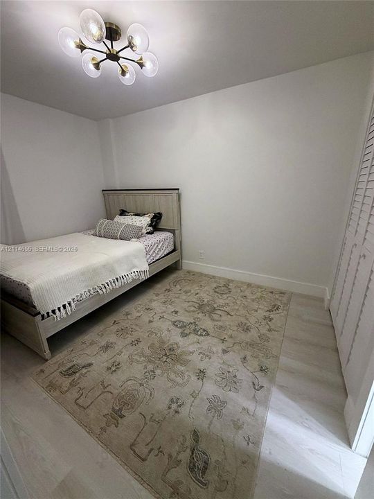 Light-toned wood-finish flooring, six-light multi-arm ceiling fixture with frosted glass shades, and bi-fold closet doors