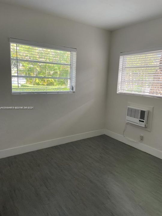Interior space featuring wood-finish flooring, two horizontal slider windows, and a wall-mounted air conditioning unit