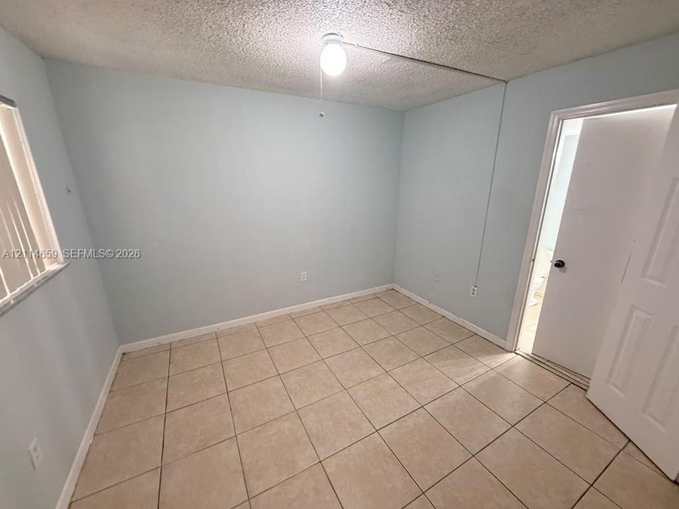 Neutral-toned ceramic tile flooring, vertical window blinds, and a central ceiling-mounted light fixture