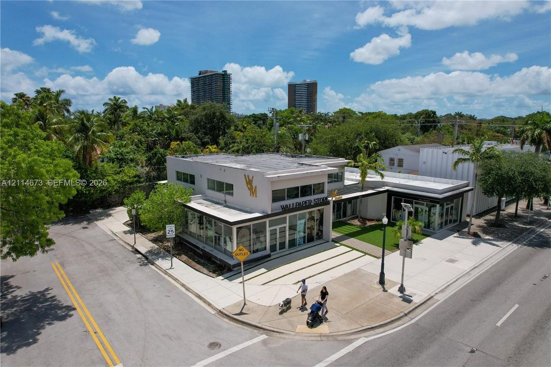 Commercial property featuring a concrete exterior, multi-level flat roof structure, expansive floor-to-ceiling glass storefront windows, and dedicated corner-lot hardscaping
