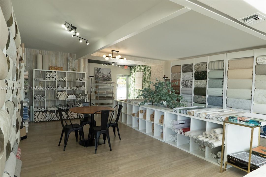 Open-concept space featuring wood-finish flooring, extensive built-in white modular shelving, and multi-directional track lighting