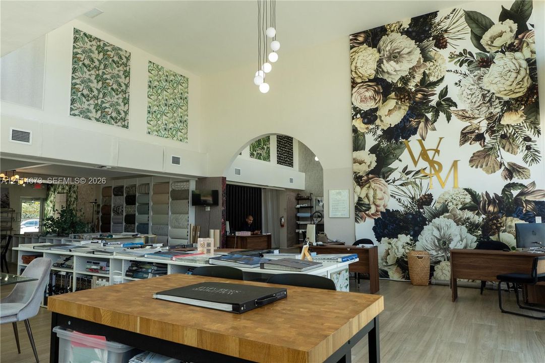 High-ceiling space featuring architectural arched pass-through, full-height decorative floral wall covering, wood-finish flooring, and multi-globe pendant lighting