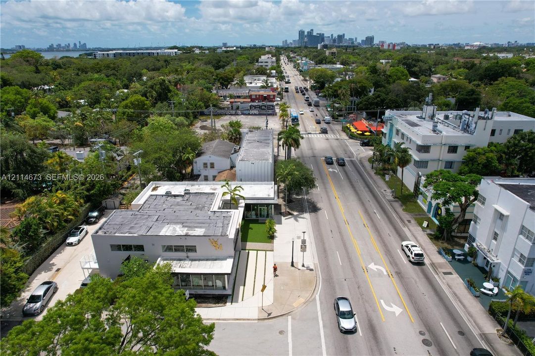 Aerial perspective showcasing a corner-lot commercial structure with a flat roof, street-level storefront glass, and paved walkway accents