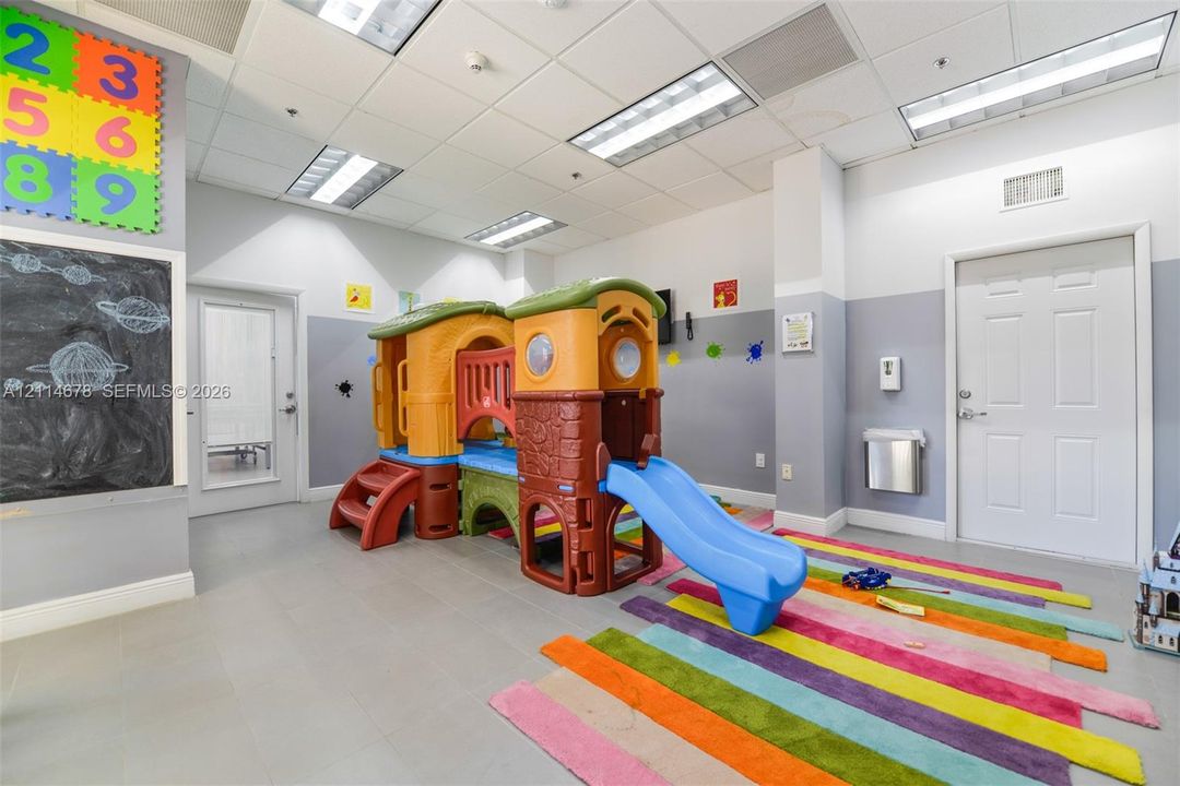 Multi-purpose interior room featuring a built-in chalkboard, recessed grid ceiling lighting, neutral wall paint, and resilient flooring