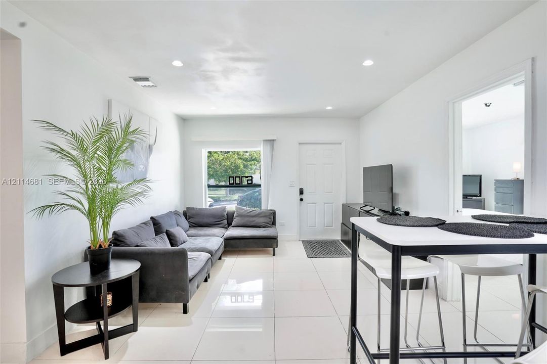 Open-concept interior featuring large-format tile flooring, recessed ceiling lighting, and natural light from a rectangular window