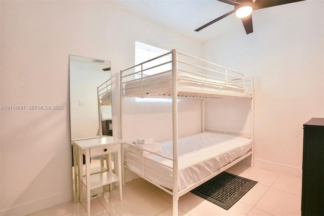 Neutral-toned tile flooring, white wall finish, and a ceiling-mounted light fixture with integrated fan