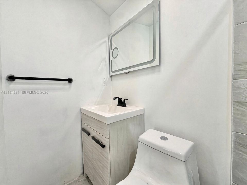 Modern vanity with a rectangular sink, matte black faucet, wall-mounted rectangular LED mirror, and matte black towel bar