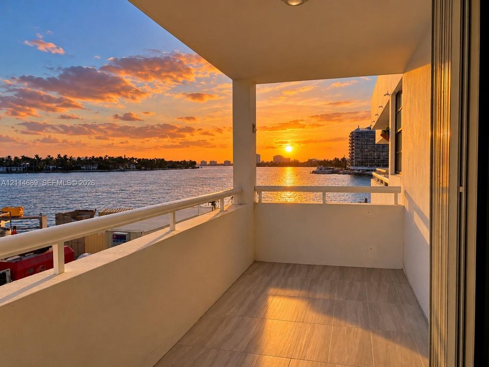 Covered balcony featuring ceramic tile flooring, a white metal railing, and expansive water exposure