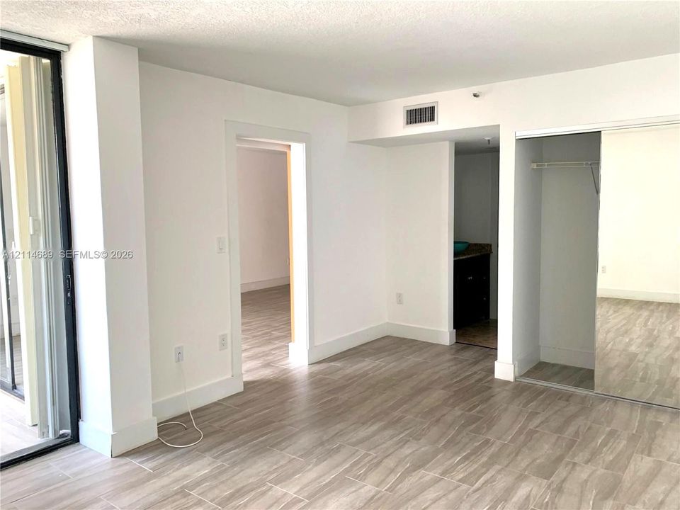 Interior featuring ceramic tile  flooring, floor-to-ceiling glass sliding door, and a built-in closet with mirrored sliding panels