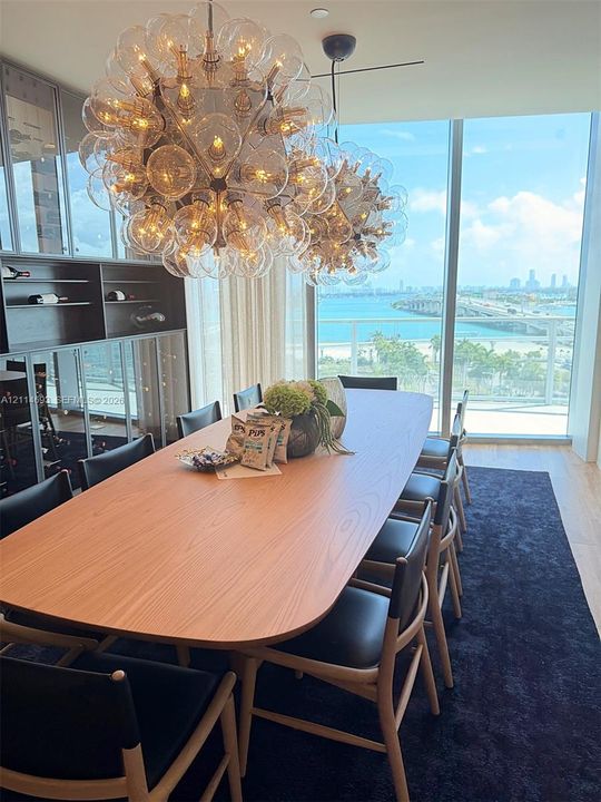 Floor-to-ceiling windows featuring coastal scenery, dual sculptural globe pendant light fixtures, and built-in wall shelving