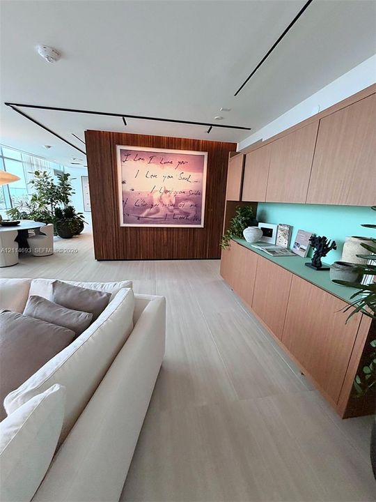 Custom wood-slat accent wall, built-in cabinetry with integrated shelving, recessed linear track lighting, and light-toned wood-finish flooring