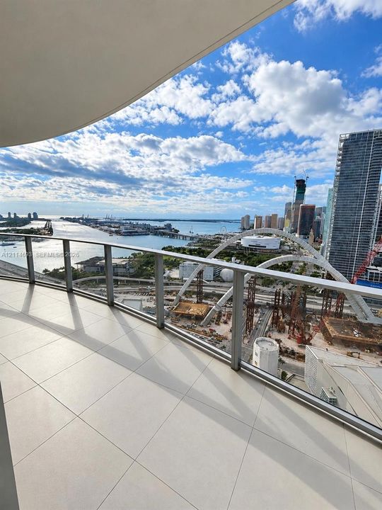 Private balcony featuring expansive ceramic tile flooring and a glass panel railing overlooking the harbor and cityscape