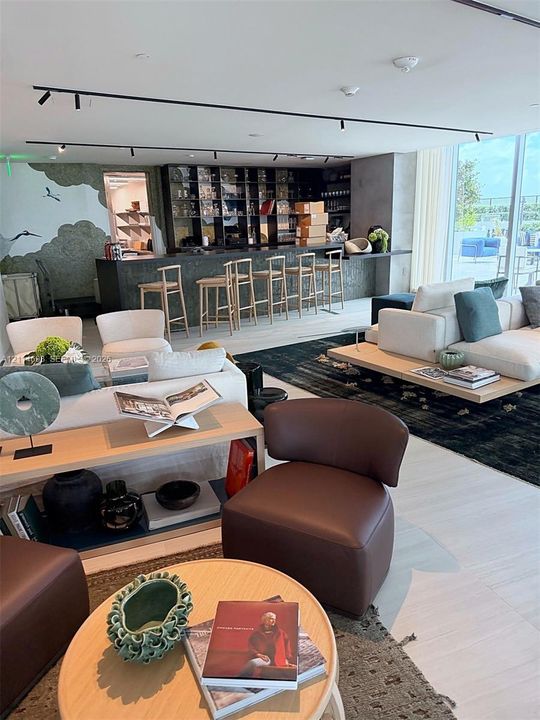 Built-in bar featuring stone-surfaced counter, recessed display shelving, track lighting, and floor-to-ceiling glass wall panels