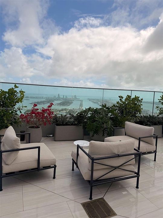 Open-air terrace featuring large-format tile flooring, frameless glass railings, and built-in concrete planters