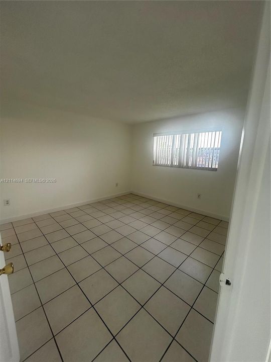 Neutral-toned interior space featuring ceramic tile flooring and vertical window blinds