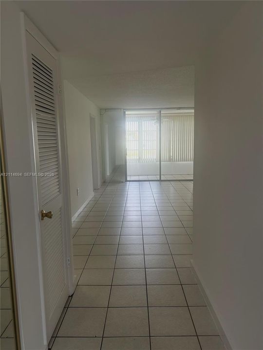 Interior area featuring square tile flooring, louvered closet door, and glass sliding doors