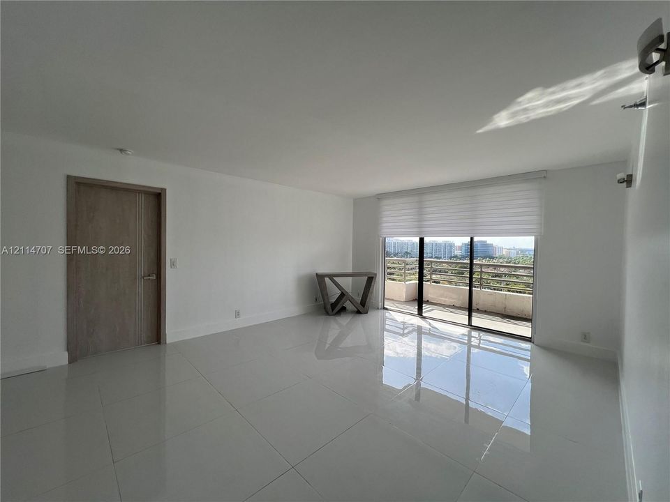 Interior space featuring polished stone-finish flooring, floor-to-ceiling sliding glass doors, motorized window shades, and a wood-finish interior door