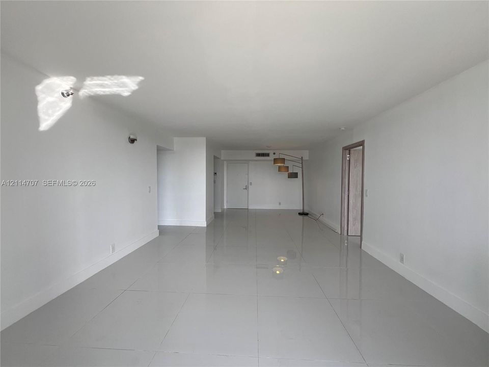 Open-concept interior space featuring high-gloss tile flooring, smooth ceilings, and interior door frames with a natural wood finish