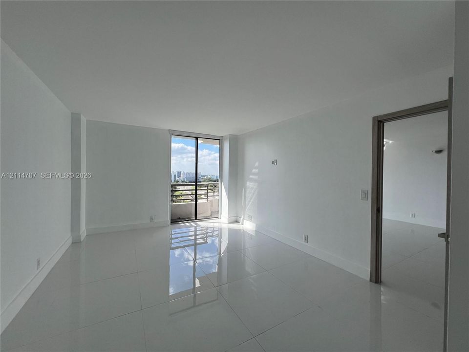 Neutral-toned interior featuring large-format tile flooring, smooth wall finishes, and a sliding glass door providing external access
