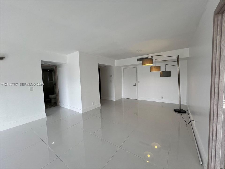 Open interior space featuring high-gloss large-format tile flooring, neutral wall finishes, recessed ceiling lighting, and solid-core interior doors