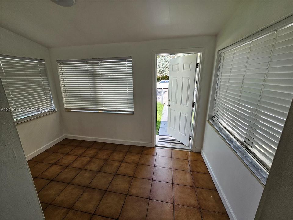 Ceramic tile flooring, multi-pane exterior door, and large windows with horizontal blinds