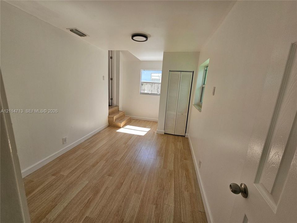 Wood-finish flooring, white walls, dual bi-fold closet doors, and recessed ceiling lighting
