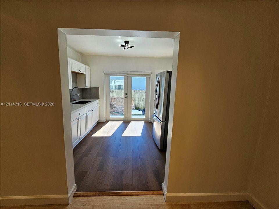 Kitchen featuring white cabinetry, wood-finish flooring, stainless steel refrigerator, and glass-paneled double doors