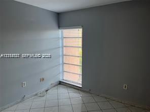 Interior space featuring neutral-toned walls, tile flooring, and a window equipped with horizontal blinds
