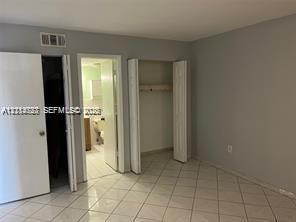Interior space featuring neutral wall paint, diagonal-set ceramic tile flooring, and two separate closet storage areas with bifold doors