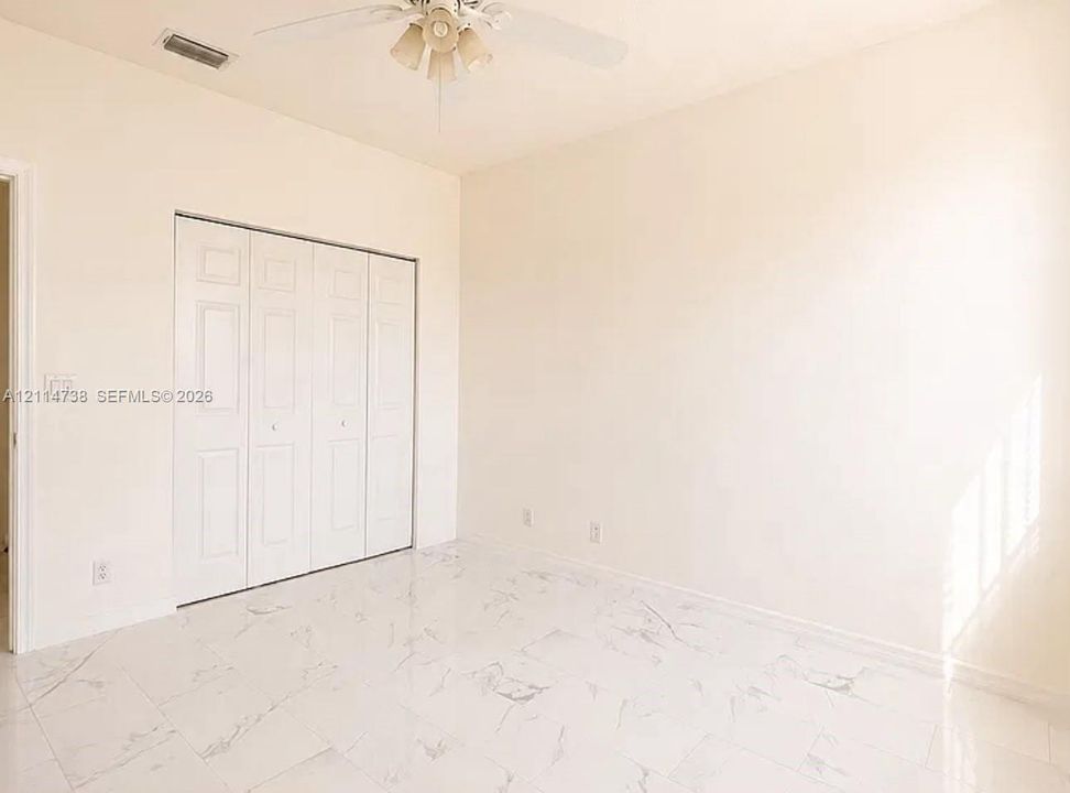 Interior space featuring high ceilings, polished stone-finish tile flooring, and a multi-panel bi-fold closet