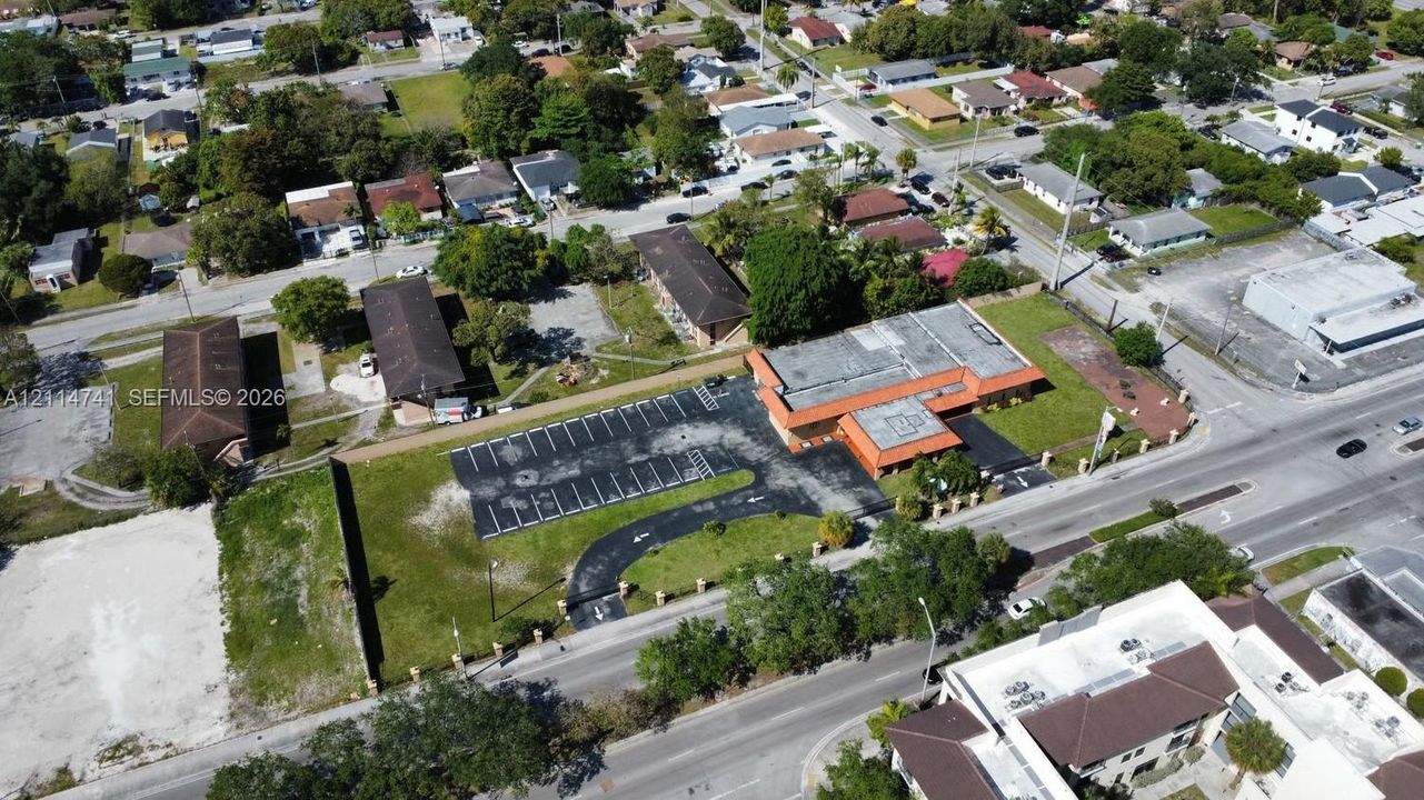 Aerial view of the commercial property featuring a flat-roof structure, expansive paved parking lot, and direct street frontage