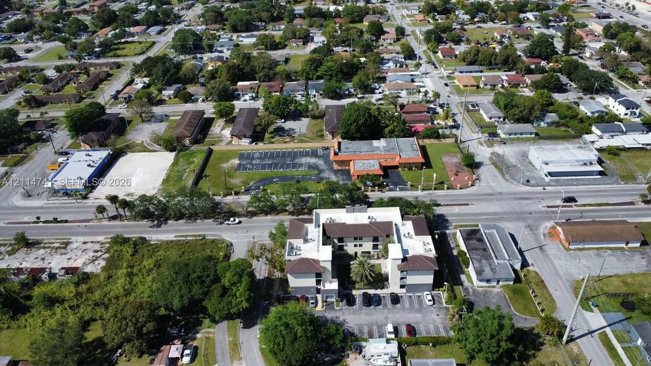 Aerial perspective of a multi-story building featuring a central courtyard, paved surface parking lot, and low-slope roof