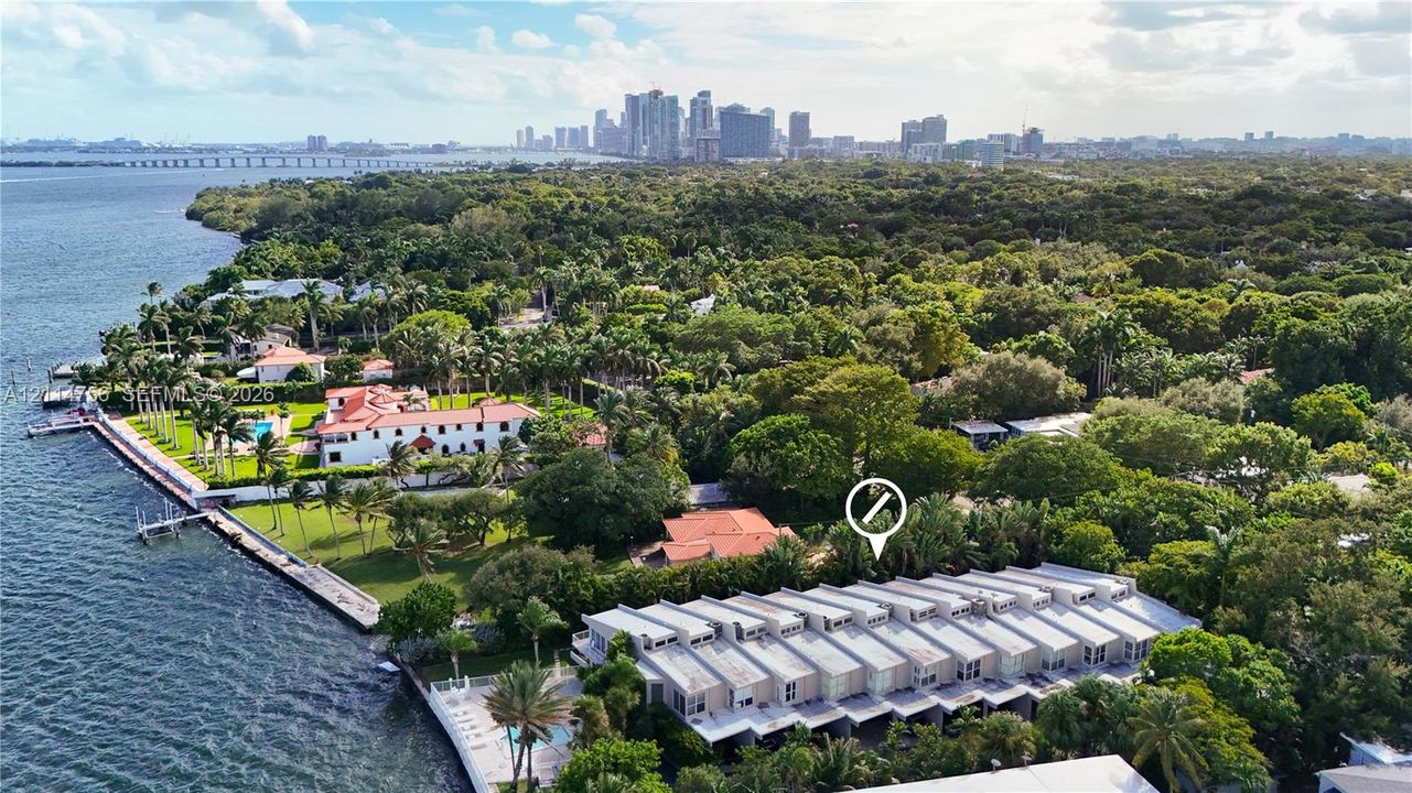 Waterfront property featuring a seawall, expansive lawn, mature landscaping, and proximity to city skyline