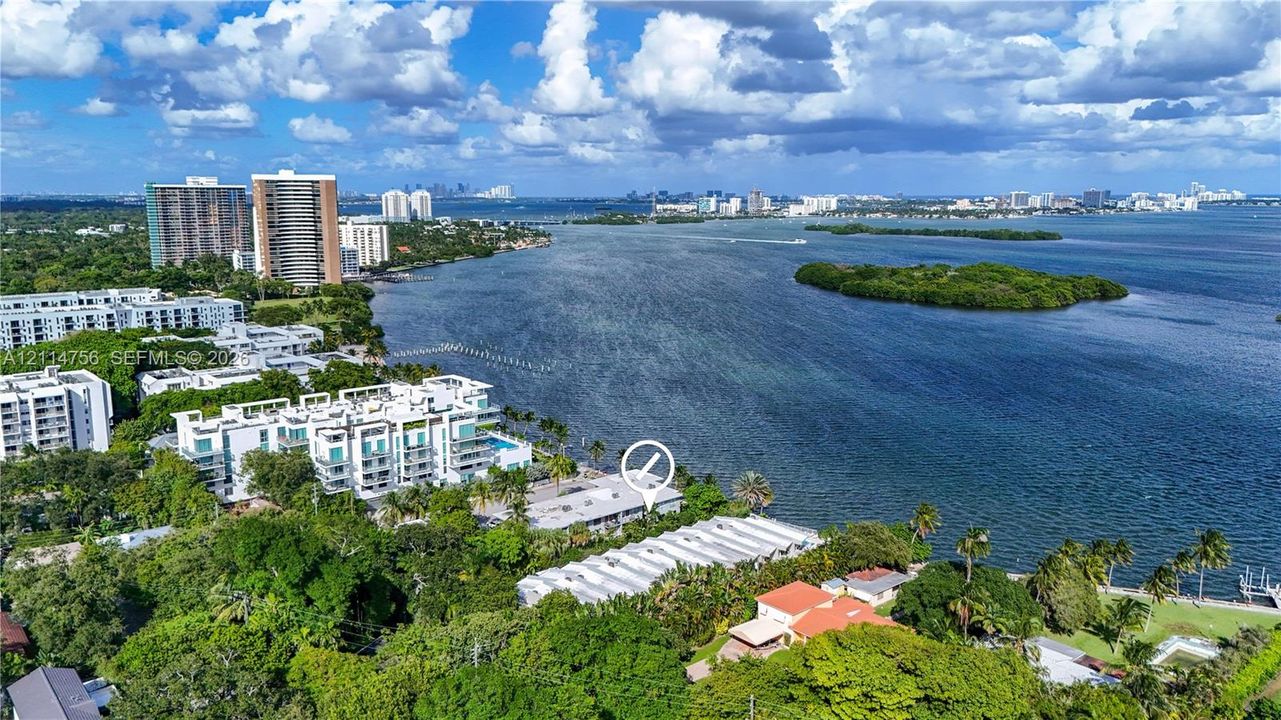 Aerial perspective of a multi-unit property situated on a waterfront parcel, featuring mature trees, dense foliage, and direct proximity to the shoreline