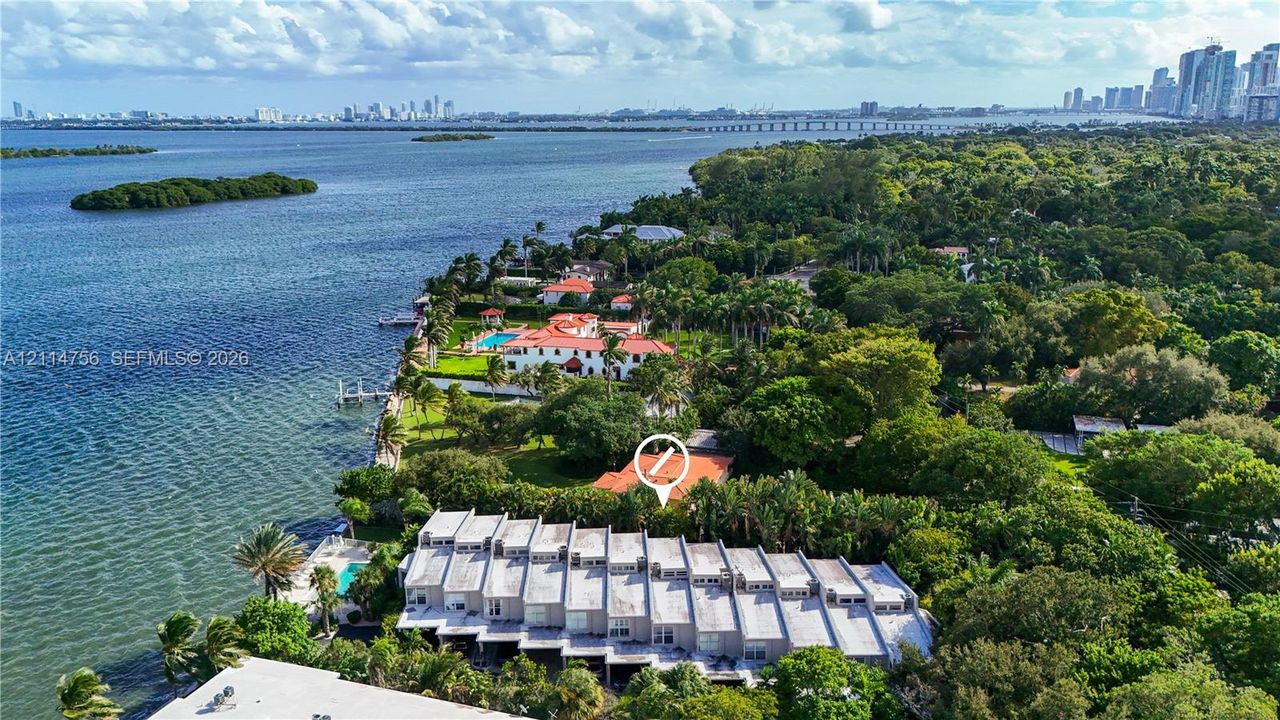 Aerial perspective of a multi-unit property featuring a tiered roofline, mature trees, and proximity to the waterfront