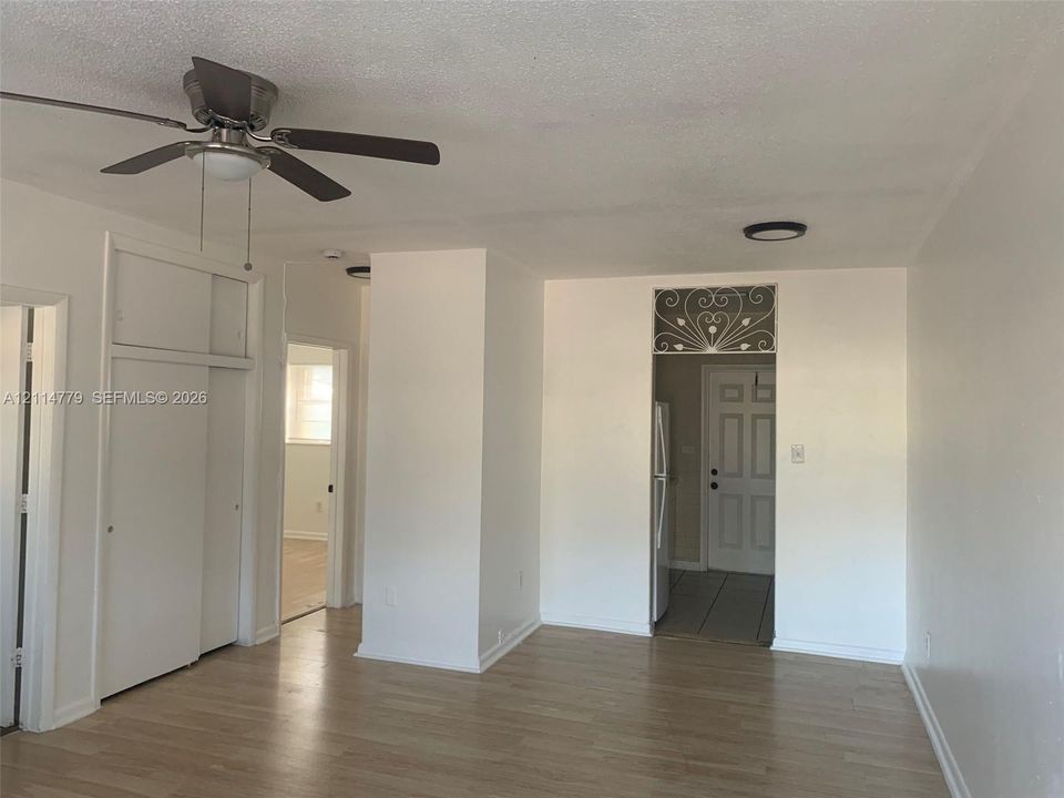 Interior featuring wood-finish flooring, a ceiling fan with integrated lighting, built-in floor-to-ceiling cabinetry, and decorative wrought iron detailing above the doorway