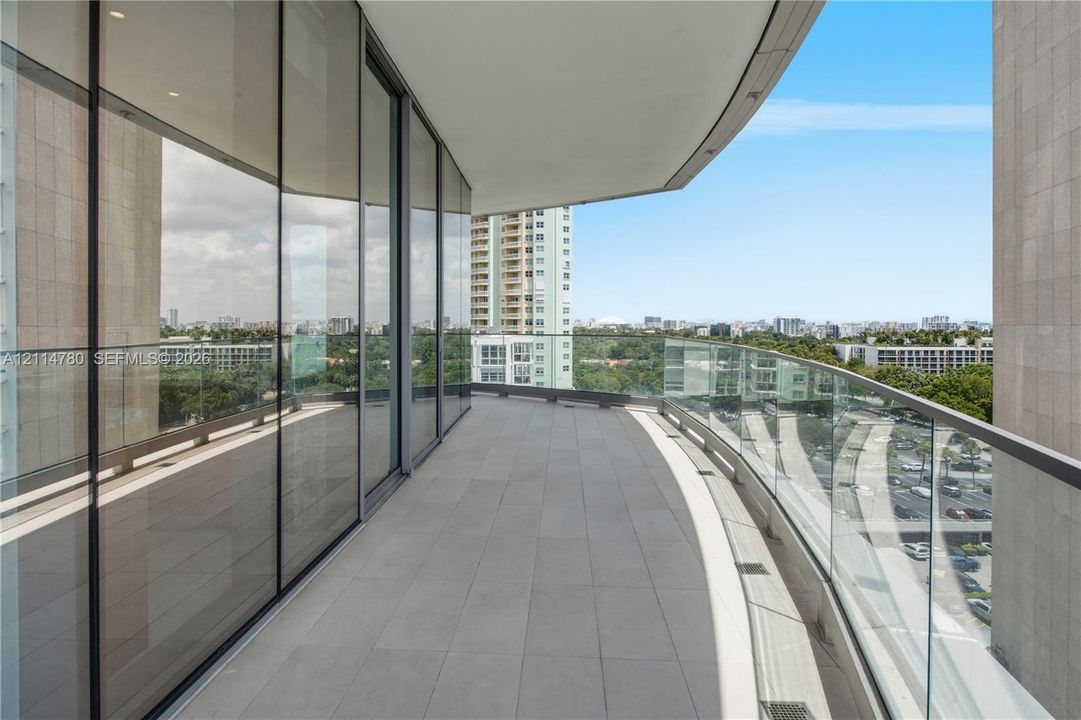 Curved balcony featuring glass railings, full-height exterior glazing, and tile flooring