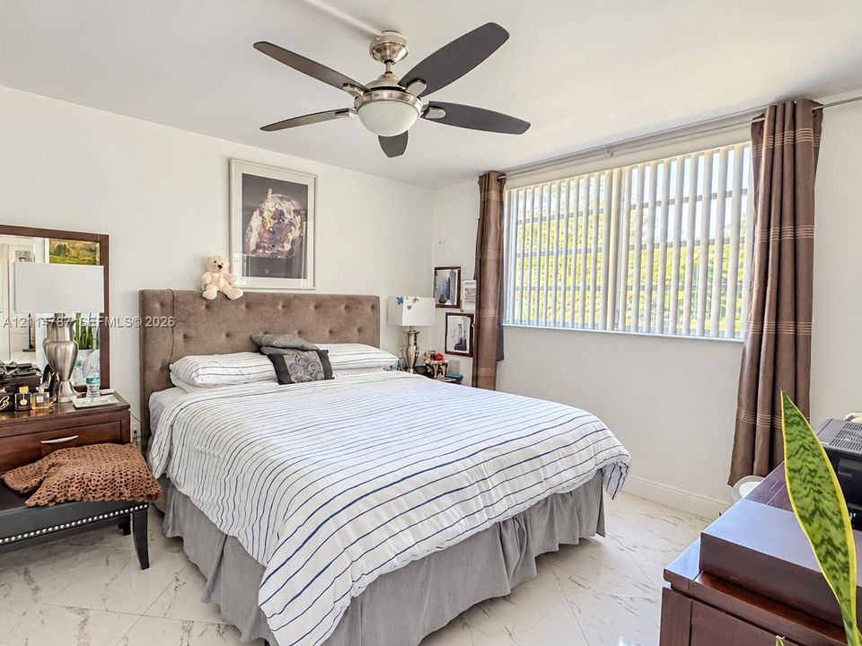 Polished stone flooring, five-blade ceiling fan with integrated lighting, and large window with vertical blinds