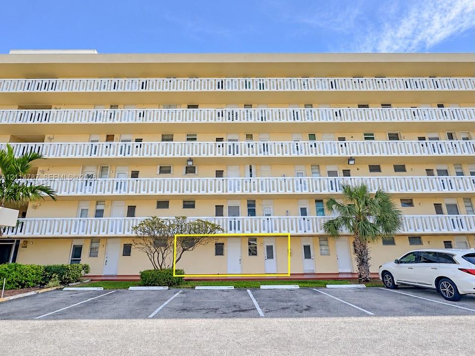 Multi-story residential building exterior featuring ground-level access, private entryway, and dedicated exterior parking space