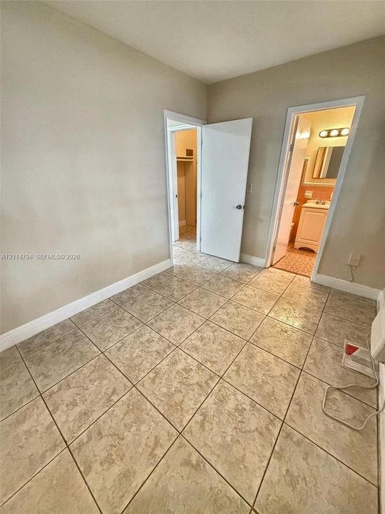 Ceramic tile flooring, neutral wall tones, built-in closet, and a bathroom featuring a vanity with an integrated sink