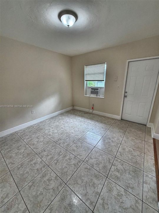 Neutral-toned interior featuring square ceramic tile flooring, a recessed ceiling-mounted light fixture, and a single-panel exterior door