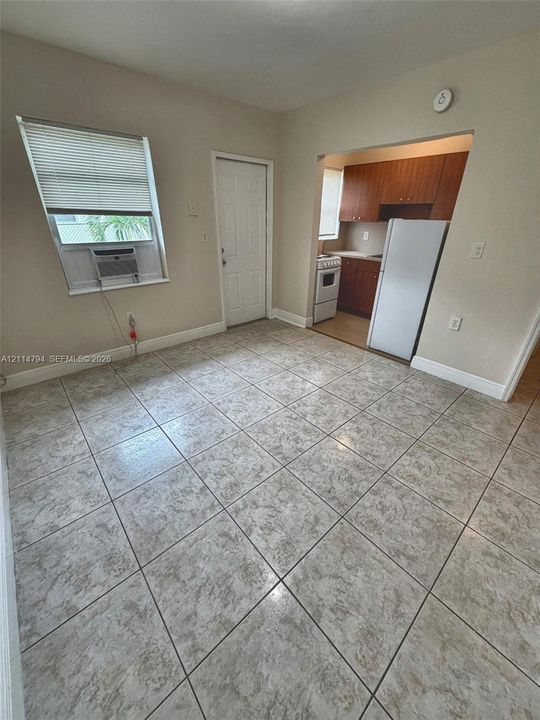 Large-format ceramic tile flooring, neutral wall paint, and kitchen featuring wood-finish cabinetry, a white refrigerator, and a white oven range