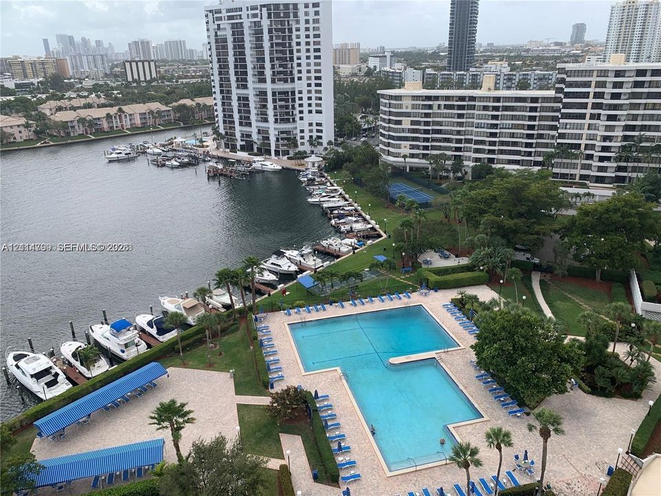 Waterfront community featuring an expansive swimming pool with hardscaped sundeck, dedicated boat slips, and mature landscaping
